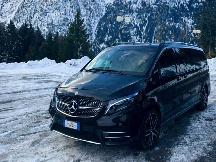 Royal Transfer's black Mercedes V-Class, with its Royal Transfer plate, parked in an alpine village in the snow